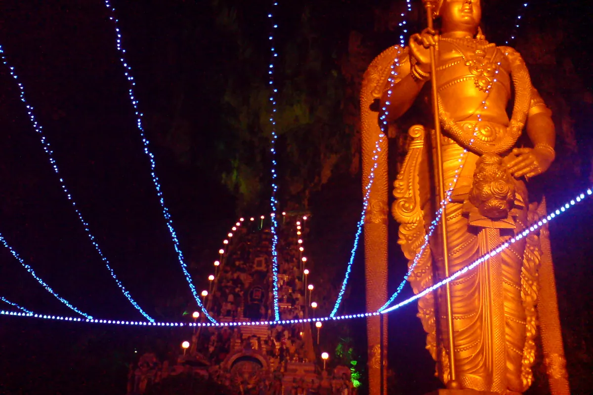 The gold Lord Murugan statue lit up at night at Batu Caves