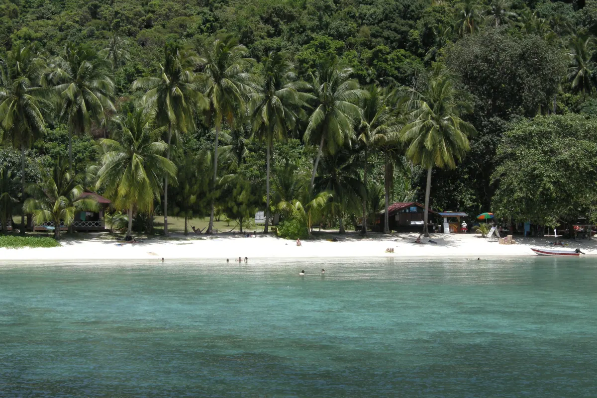 Long-tail boats moored in clear shallow water off a Perhentian island beach
